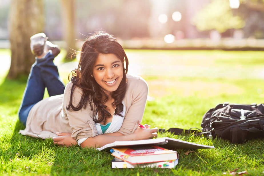 A shot of an asian student studying on campus lawn